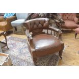 An Edwardian walnut framed horseshoe back tub chair upholstered in brown hide, with relief carved