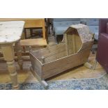 A 19thc pine cradle with arched top and shaped splay sides, complete with rockers, evidence of