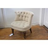 An early 19thc style low chair with button back, in cream linen, with studded detail, on turned