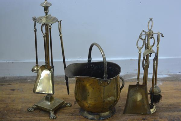 A four piece brass companion set on circular urn finial stand and paw feet, complete with brush etc.