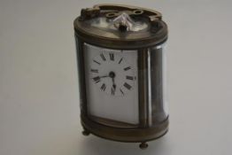 An Edwardian French oval brass four glass carriage clock with brass handle to top, with enamel