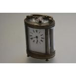 An Edwardian French oval brass four glass carriage clock with brass handle to top, with enamel