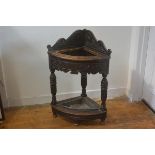 A late 19thc oak carved corner hall stick stand with relief carved shaped panel back and frieze,