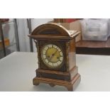 An Edwardian walnut mantle clock with arched top above an enamelled dial with twin key apertures and