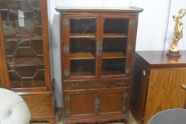 A Chinese elm and cherrywood display cabinet, the top with outswept edge, above a pair of glazed