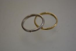 An 18ct yellow gold wedding band (2.23g) and a white metal cut wedding band (3.82g) (2)