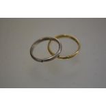 An 18ct yellow gold wedding band (2.23g) and a white metal cut wedding band (3.82g) (2)