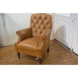 A modern Victorian style tan hide button back club style chair with scroll arms, raised on turned