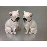 A pair of late 19th century Staffordshire large models of seated pugs, cream glazed and with black