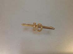 An Edwardian gold (unmarked) and seed pearl "birthday" brooch, the knife edge bar mounted with a "