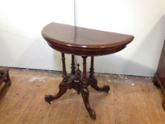 A Victorian walnut demilune foldover card table, the top with moulded edge over a four column