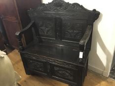 A late Victorian carved oak hall settle, the panelled back with shell and scroll carved crest, the