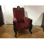 A late Victorian carved walnut gentleman's armchair, the scroll carved crest rail centred by a