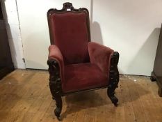 A late Victorian carved walnut gentleman's armchair, the scroll carved crest rail centred by a