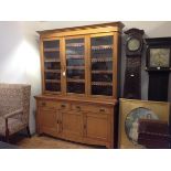 A golden oak bookcase cabinet c. 1900, the upper section with moulded cornice above three glazed