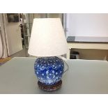 A Chinese style blue and white porcelain table lamp, decorated with flowering branches, on an
