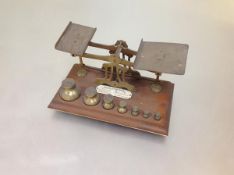 A set of early 20th century brass postal scales, the mahogany base with a full set of weights,