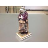 A 19th century Continental porcelain figure of a beggar worman, in Naples style, modelled in