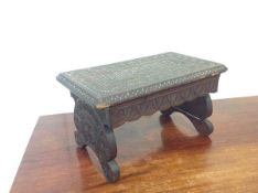 A chip-carved oak low stool, on trestle legs. 23cm by 41cm by 25cm