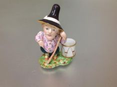 An English porcelain Mansion House dwarf figure, unmarked, modelled standing with a staff, a drum at