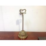An Edwardian brass door stop, the lead weighted base in relief with ribbon-tied swags on a long stem
