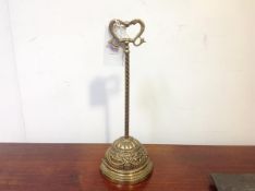 An Edwardian brass door stop, the lead weighted base in relief with ribbon-tied swags on a long stem