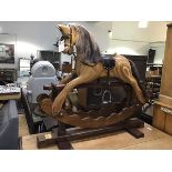 An Ian Armstrong rocking horse of laminated sectioned pine, complete with leather saddle, with