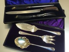 A set of three Edwardian servers including fish and fruit and a horn handled three piece carving set