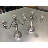 A pair of Epns three branch candelabra raised on circular moulded bases complete with drip trays (