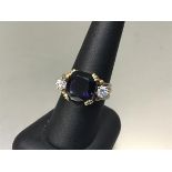 A 22ct yellow and white metal ring set cushion cut blue stone flanked by a diamond to each