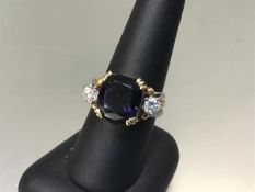 A 22ct yellow and white metal ring set cushion cut blue stone flanked by a diamond to each