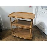 An Ercol light elm three tier trolley with moulded edges, raised on turned supports, complete with
