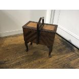 A mahogany concertina sewing box with centre handle enclosing a fitted interior, on carved moulded