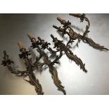 A set of four Louis XV style gilt metal two light wall sconces, each with leaf cast scrolling back