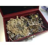 A box containing a large collection of paste pearl necklaces, bracelets, gilt metal chains,