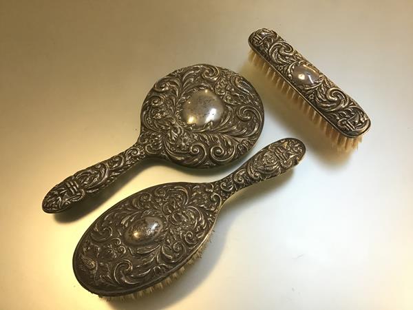 A Birmingham silver chased hand mirror with matching clothes brush and hairbrush, (mirror and brush: