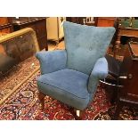 A 1950s tub chair with button back, upholstered arms and stuffover seat, in blue plush, raised on