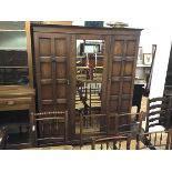 An oak wardrobe, the moulded cornice above a centre mirror door, flanked by inset panel doors, on