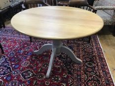 A modern extending circular top oak kitchen dining table with extension magic leaf, raised on turned