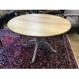 A modern extending circular top oak kitchen dining table with extension magic leaf, raised on turned