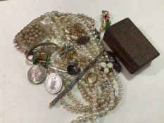 A collection of costume jewellery including paste pearls, brooches, medallions, wristwatches, a WWII