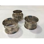 A pair of London silver hammered finish napkin rings, with stylised floral and leaf design in the