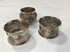 A pair of London silver hammered finish napkin rings, with stylised floral and leaf design in the