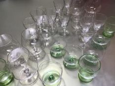 A collection of mid century glassware including green glass tumblers, dessert glasses, brandy