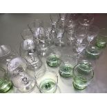 A collection of mid century glassware including green glass tumblers, dessert glasses, brandy