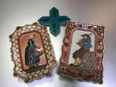 A pair of Breton pottery plaques depicting Man with Bagpipes and Lady with Fishing Basket, decorated