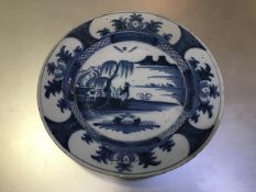 An 18thc Delft plaque c.1750, decorated with figure in landscape (d. 35cm) (restorations, fritting