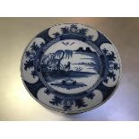 An 18thc Delft plaque c.1750, decorated with figure in landscape (d. 35cm) (restorations, fritting