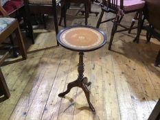 A mahogany pedestal wine table with saucer top and inset skiver on turned column and tripod