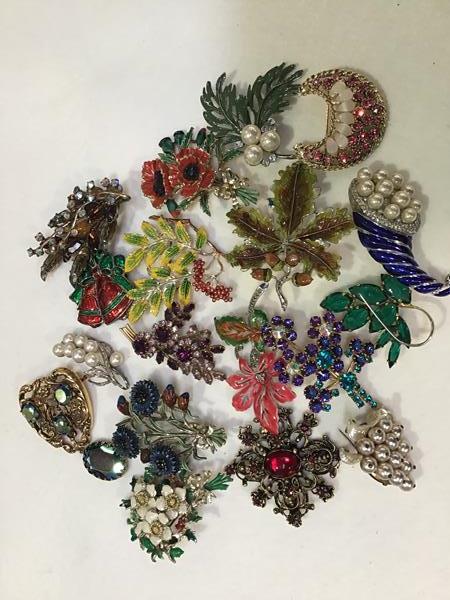A collection of enamelled and paste floral style brooches including Christmas bells, spray